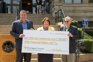 Shawn Ball, Carolyn Long and Gordon Gee hold a check during a presentation.