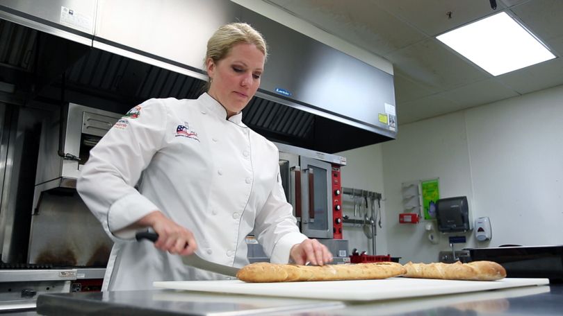 Chef Devin Noor, dressed in her white chef coat, demonstrates bread prep in a WVU Tech test kitchen.