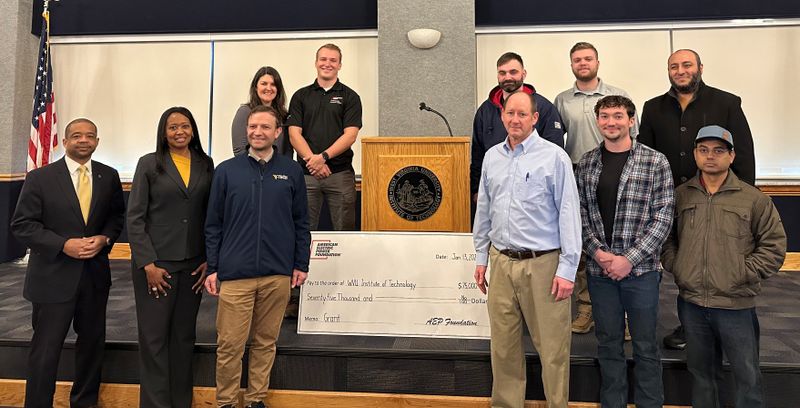 A group of students, faculty and representatives from Appalachian Electric Power stand with a check for $75,000