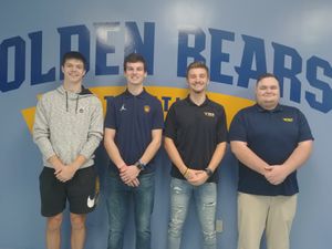 Four Students stand in front of Golden Bears Mural 