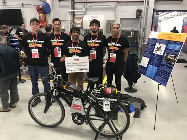 The team stands alongside their bike at a competition in Ames, Iowa.