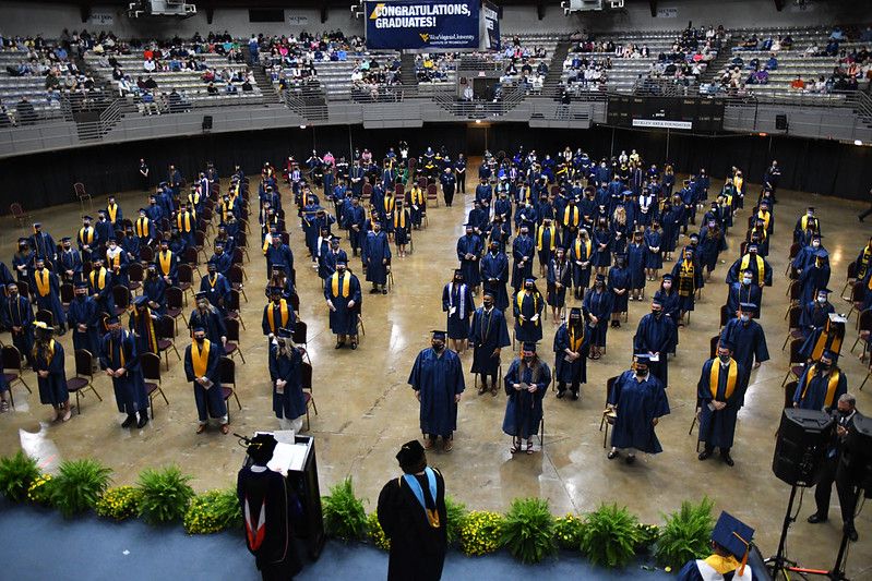 An image of the convention center, gold and blue-clad graduates standing in the auditorium with hundreds of friends and family looking on.